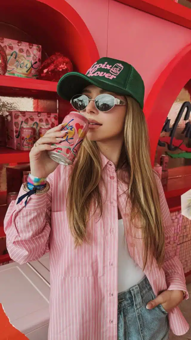 a woman wearing a hat and holding a can